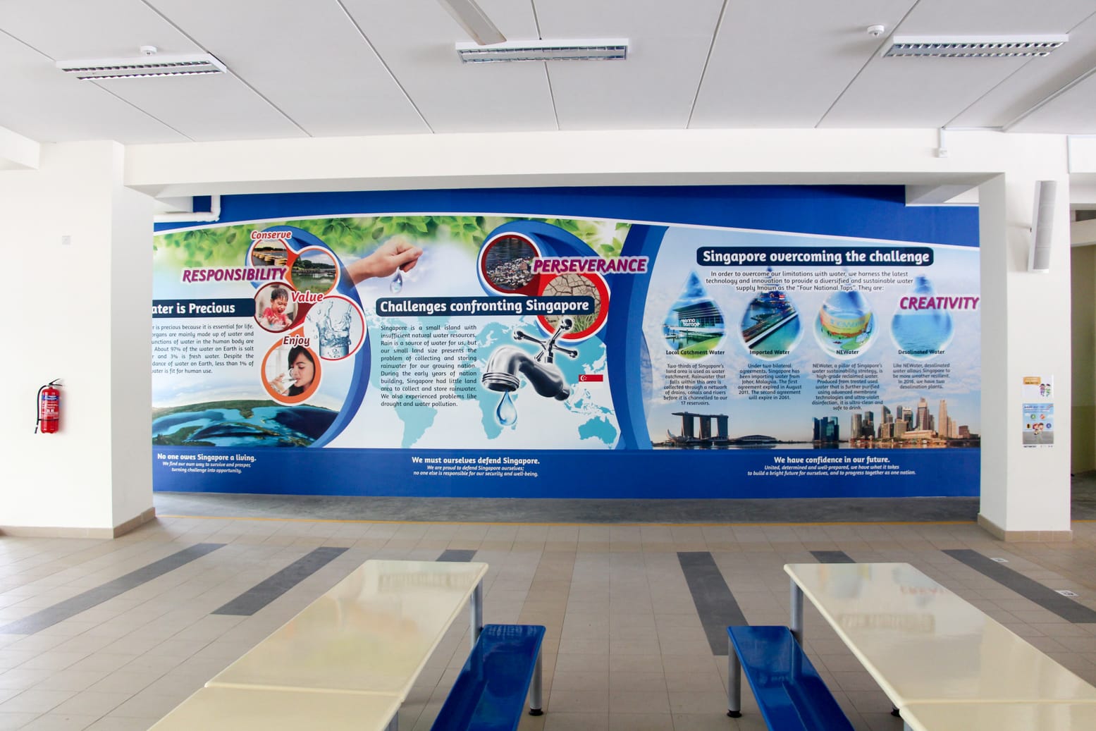 A large blue educational mural about Singapore's water challenges and solutions on a school canteen wall.